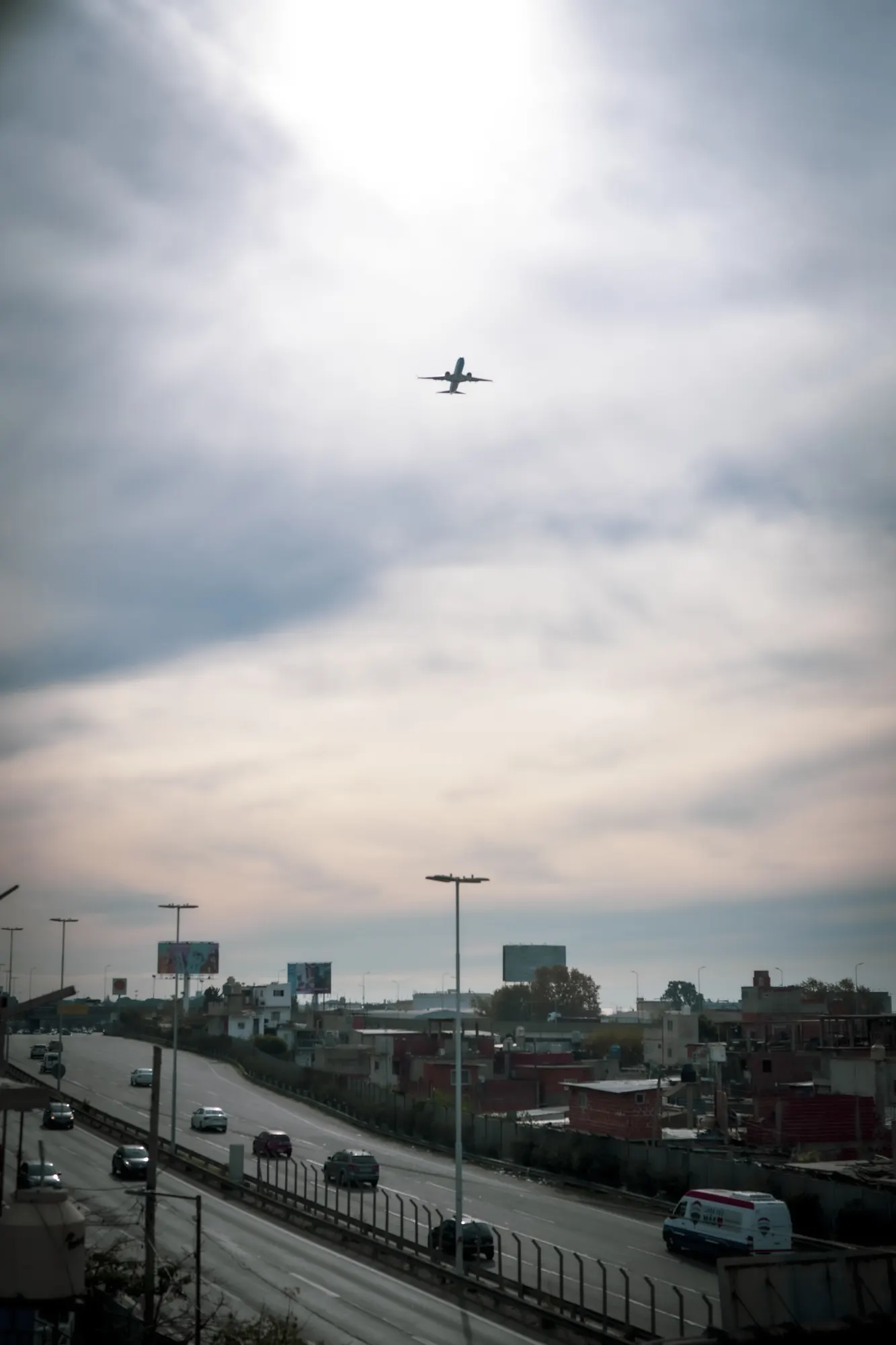 La autopista Illia desde el barrio, con un avión cruzando el cielo