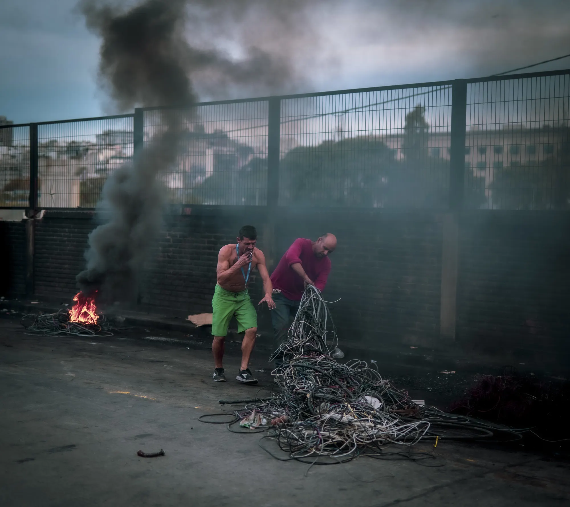 Dos hombres separando cables entre el humo