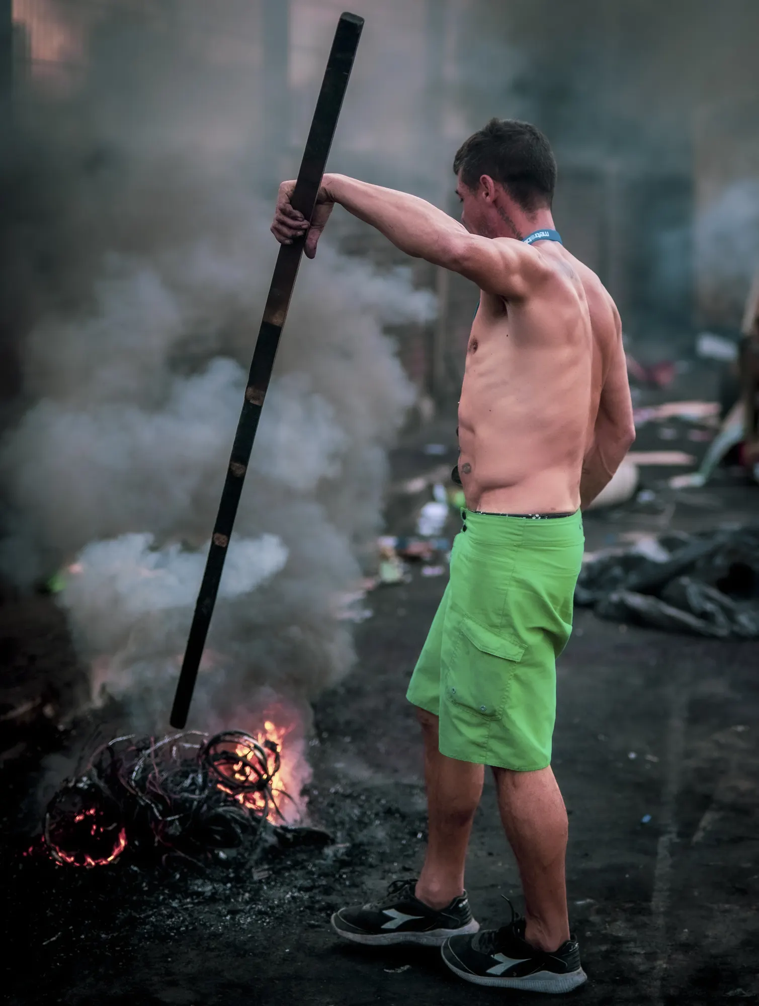 Un hombre con un palo de hierro frente al fuego