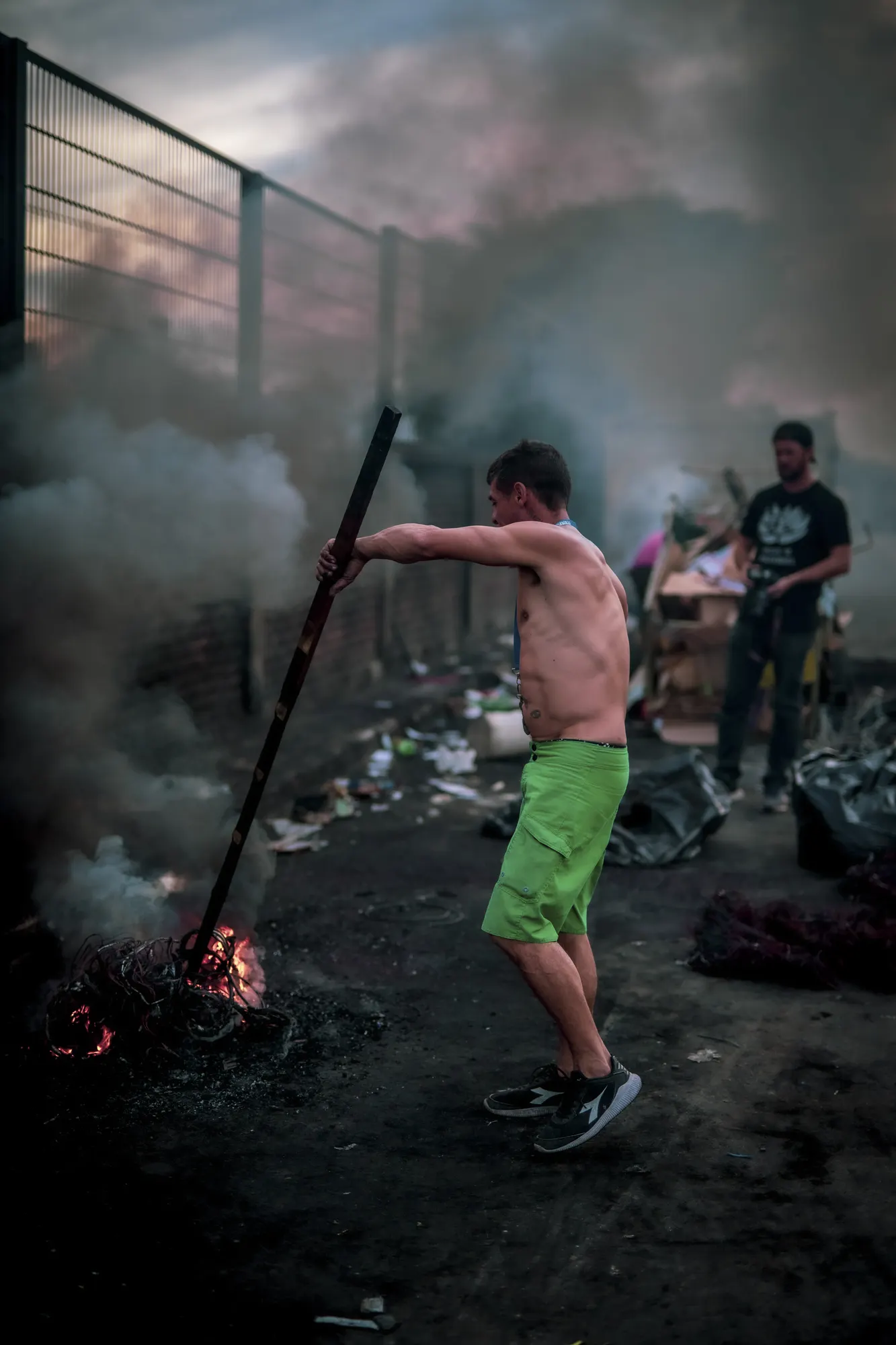 Un hombre removiendo el fuego con un palo entre el humo