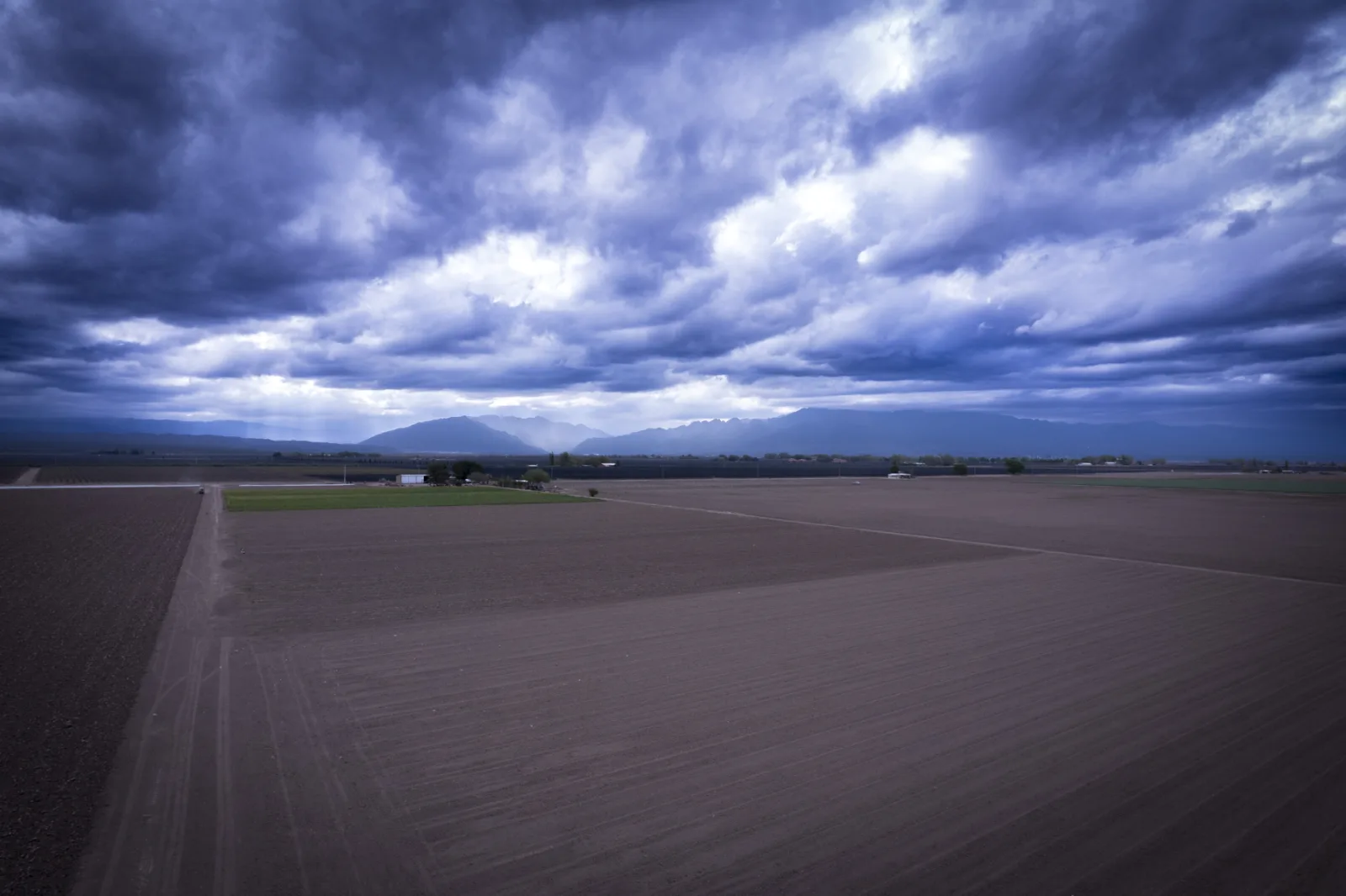 Vista aérea de campos cultivados de Mendoza con la cordillera de los Andes al fondo y cielo de tormenta